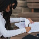 Crop ethnic office employee making schedule at table